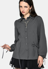 A woman modeling a dark gray and black vertically striped button-up shirt with a pointed collar, long sleeves, and side drawstrings, paired with a black lace hem dress against a light gray background.