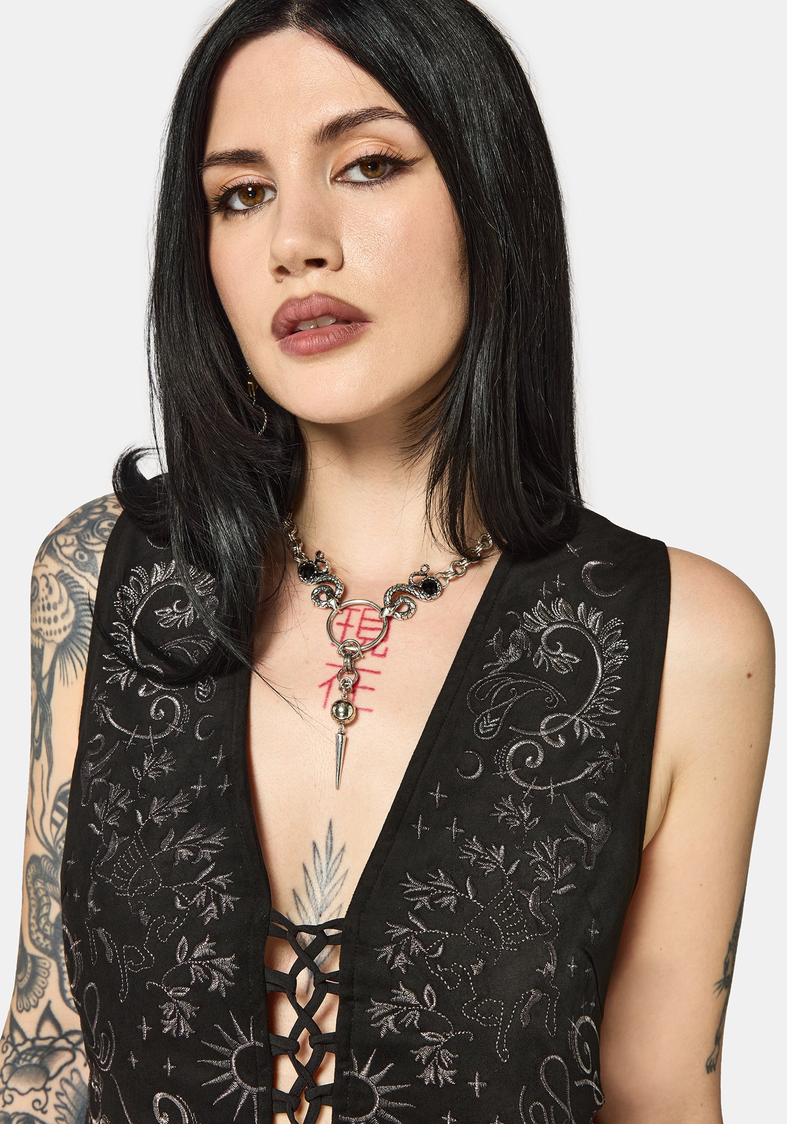 Woman wearing a black embroidered vest with floral patterns on a white background
