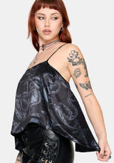 Woman wearing a black printed satin top with leather pants against a white background