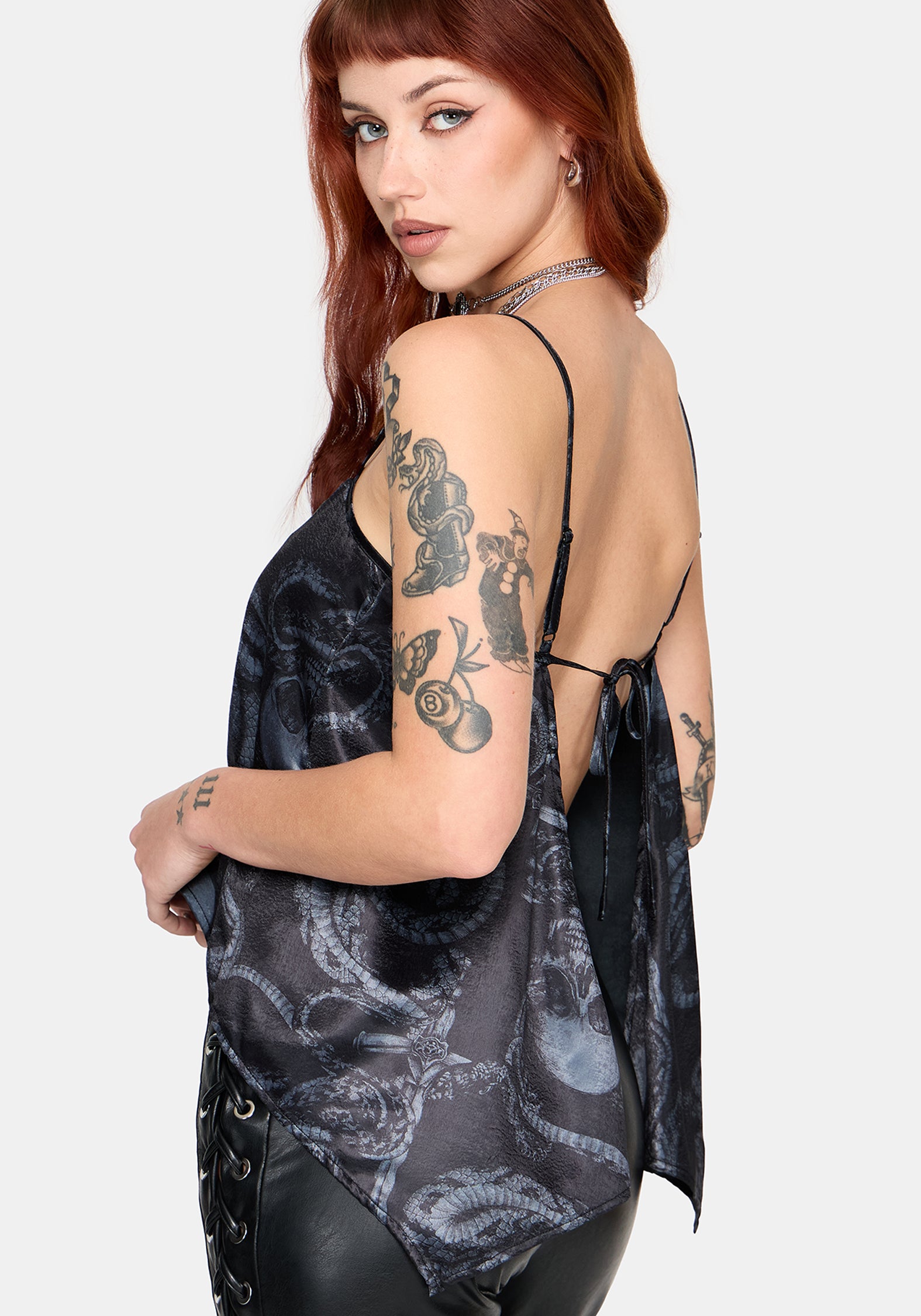 Woman wearing a black printed satin top with leather pants against a white background
