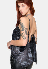 Woman wearing a black printed satin top with leather pants against a white background