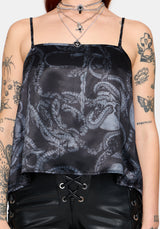 Woman wearing a black snake printed satin top with leather pants against a white background
