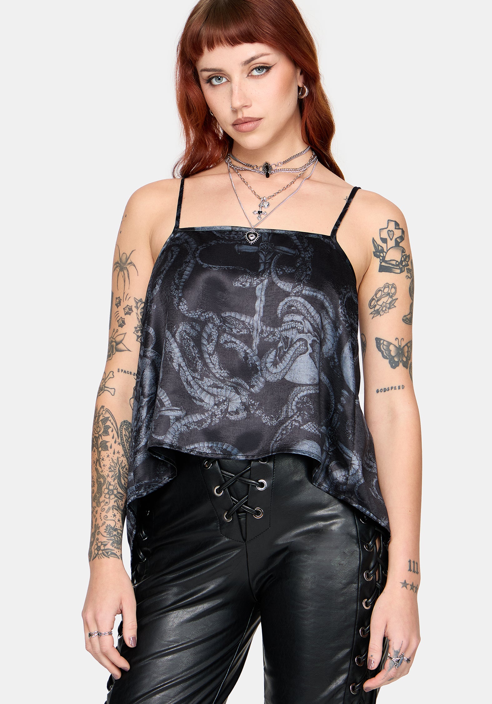 Woman wearing a black snake printed satin top with leather pants against a white background