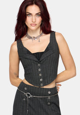 A woman modeling a dark gray pinstriped sleeveless vest corset with a button-front detail, paired with a matching skirt and silver accessories, against a light gray background.