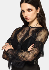 Woman wearing a black lace long sleeve top against a white background