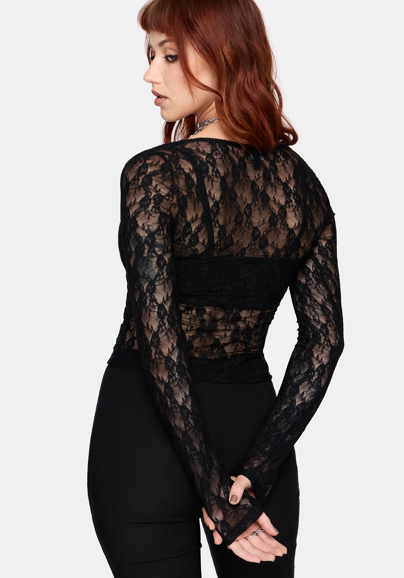 Woman wearing a black long sleeve lace top against a white background