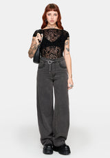 Woman wearing a black lace top and gray straight leg jeans on a white background
