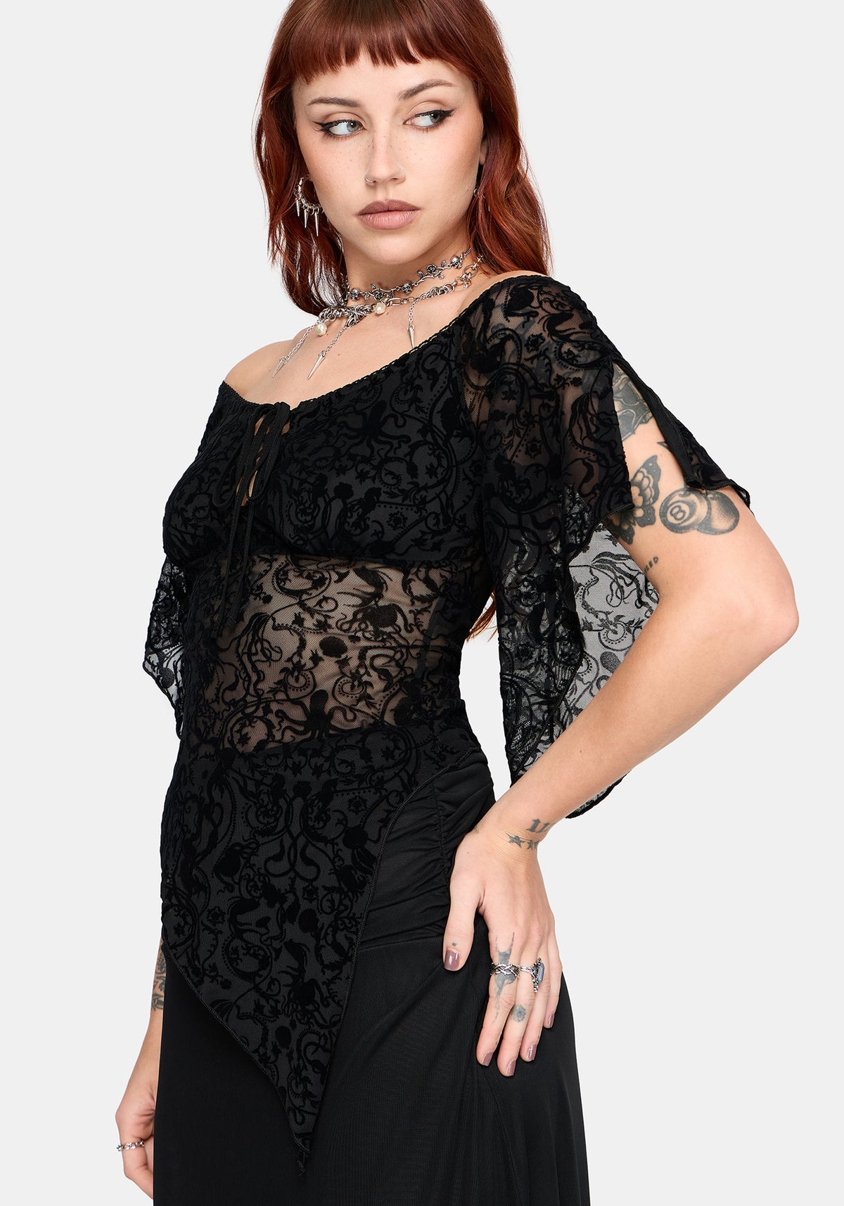 Woman wearing a black lace flared sleeve top against a white background
