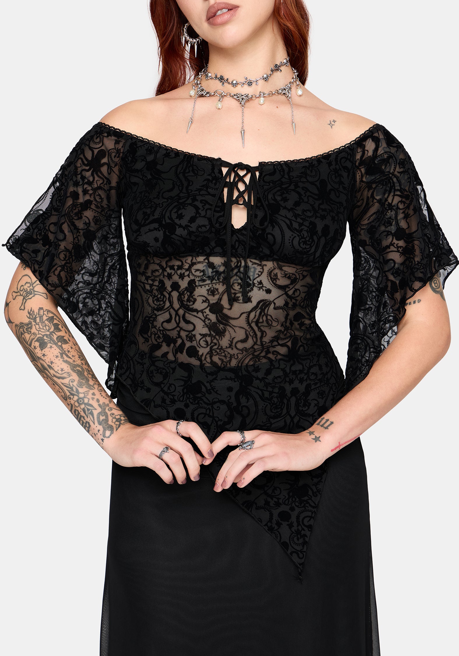 Woman wearing a black lace top with sheer sleeves on a white background