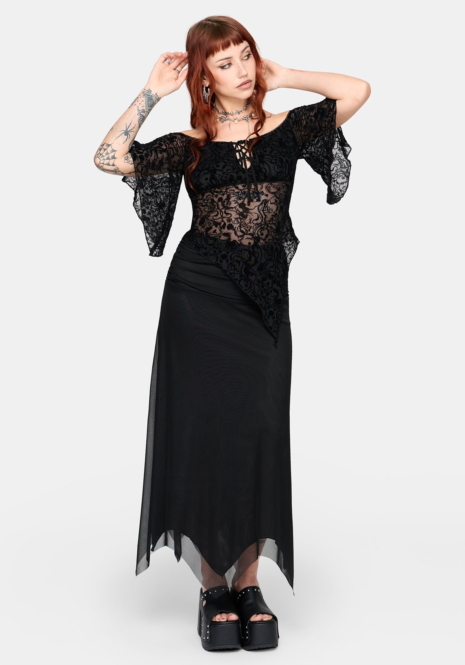 Woman wearing a black lace top and black skirt on a white background