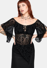 Woman wearing a black lace top with flared 3/4 sleeves and sheer panels on a white background