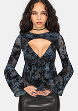 A woman modeling a black and blue patterned camisole top with thin straps and a ruffled peplum, paired with a black faux-leather skirt, against a light gray background.