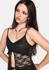 A woman wearing a black lace camisole top with thin straps, a ruched sweetheart neckline, and a side slit, paired with silver statement jewelry against a light gray background.