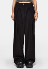 A model wearing black wide-leg pleated trousers with a button closure at the waist, styled with black platform shoes and a gray textured crop top against a light gray background.