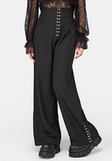 Black wide-leg trousers with decorative silver-tone lace-up detailing at the waistband and along the outer lower leg, shown on a model against a light gray studio background.
